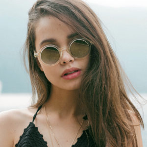 Modella castana con occhiali da sole tondi, con lago di Como sullo sfondo
